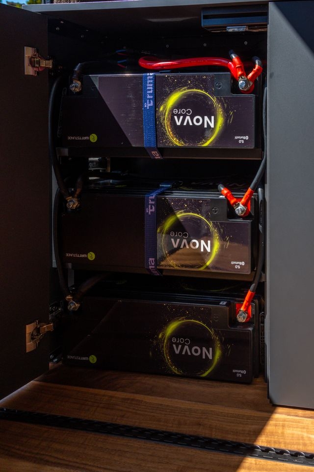 Drei Lithium Batterien für genügen Speicherkapazität wurden von Cocoon Vans eingebaut. Die Batterien sind in einem verschliessbaren, grauen Möbel eingebaut. Der Boden des Fahrzeugs ist aus amerikanischem Nussbaum mit eingelassenen Airlineschienen.