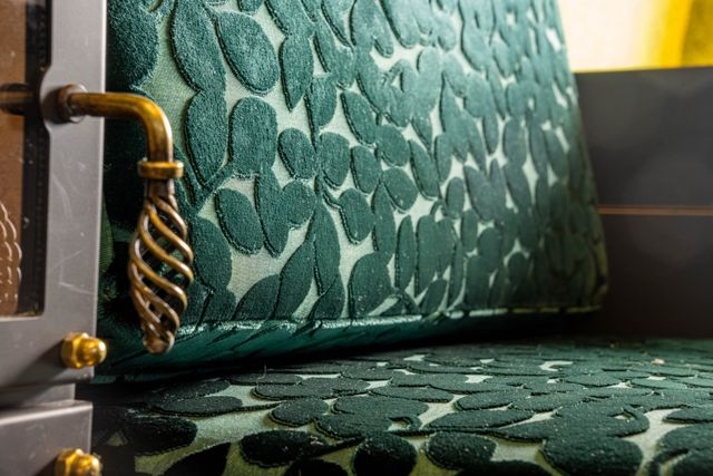 Detailaufnahme der Sitzecke aus samtgrünen Stoff mit Blumenmuster. Am Rand ist noch der Türgriff vom Tiny Stove zu sehen.